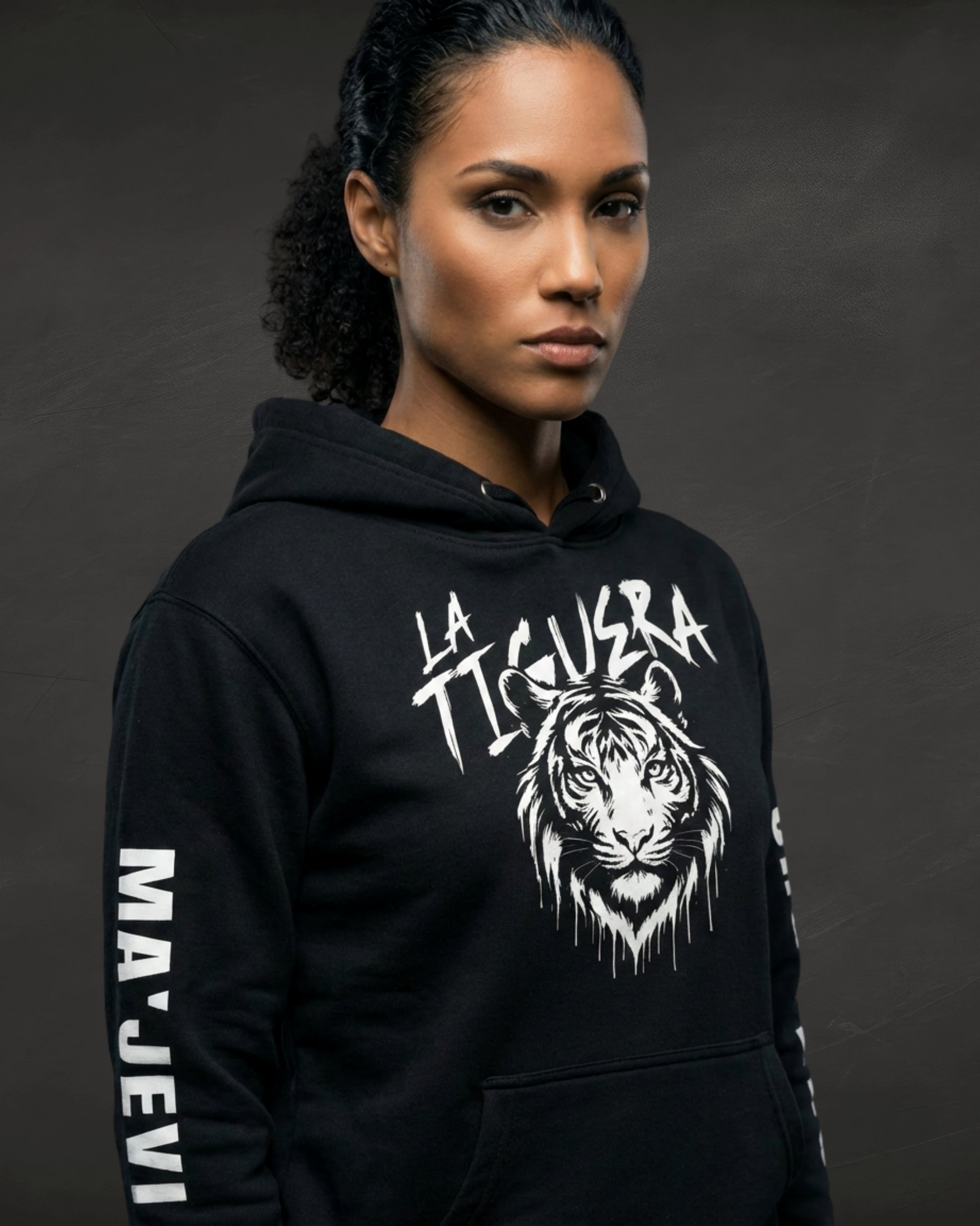 Person wearing a black hoodie with a tiger design and text on a dark background