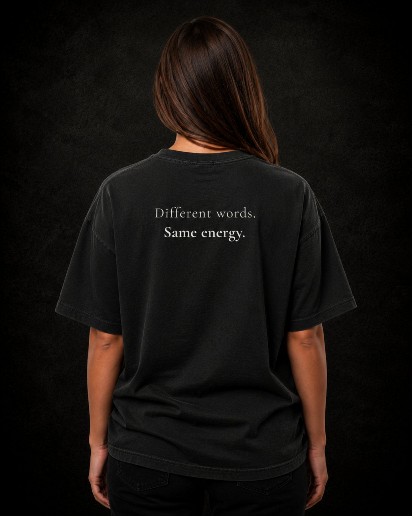 Latina wearing a washed black t-shirt with text on the back against a dark background
