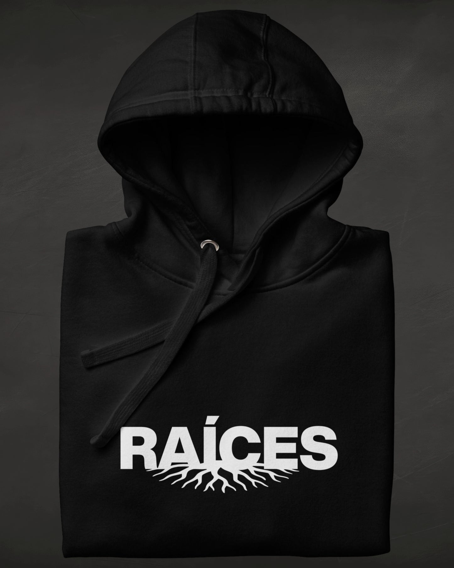 Black hoodie with 'RAÓCES' text and root design on a dark background